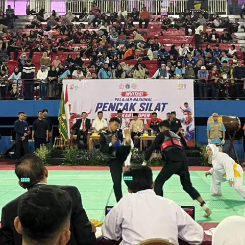 Dua pesilat remaja bertanding di hadapan wasit dengan tribun GOR Ciracas yang dipenuhi penonton dalam Invitasi Pelajar Nasional Pencak Silat Jakarta Open 2026.